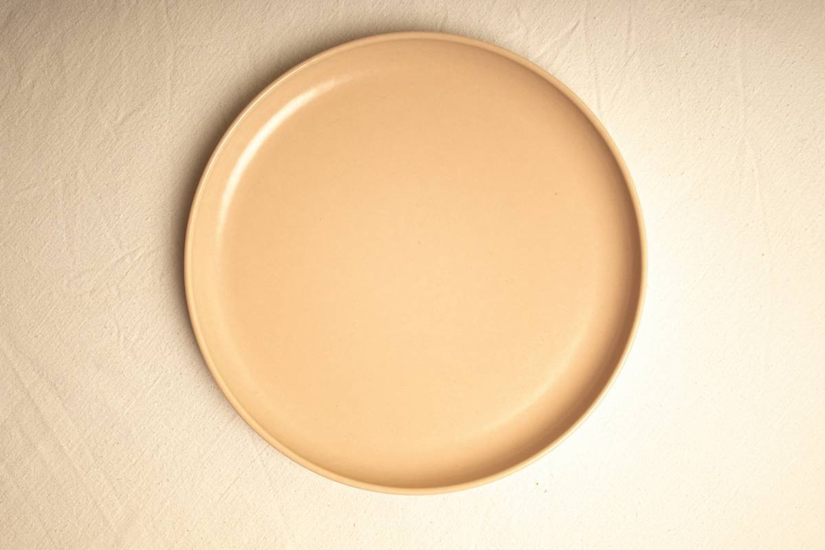 A frustrated person holding a spatula while staring at an empty fridge